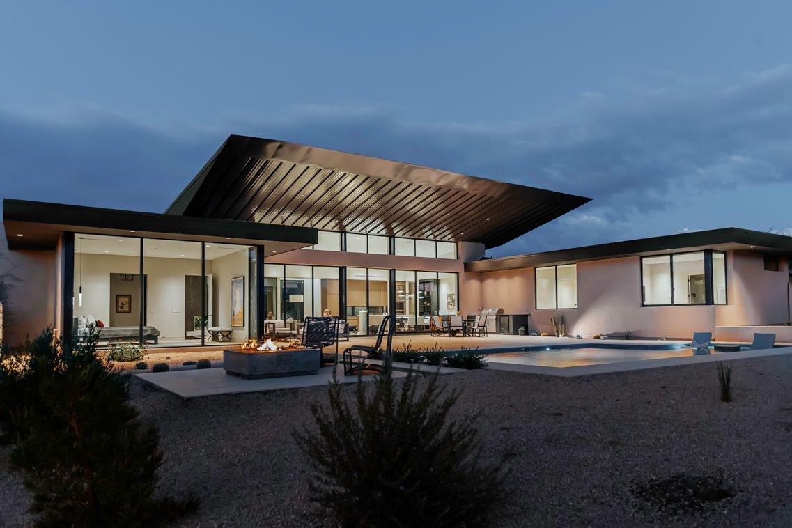 Angled exterior view of modern residence with desert boulders and covered patio in Carefree