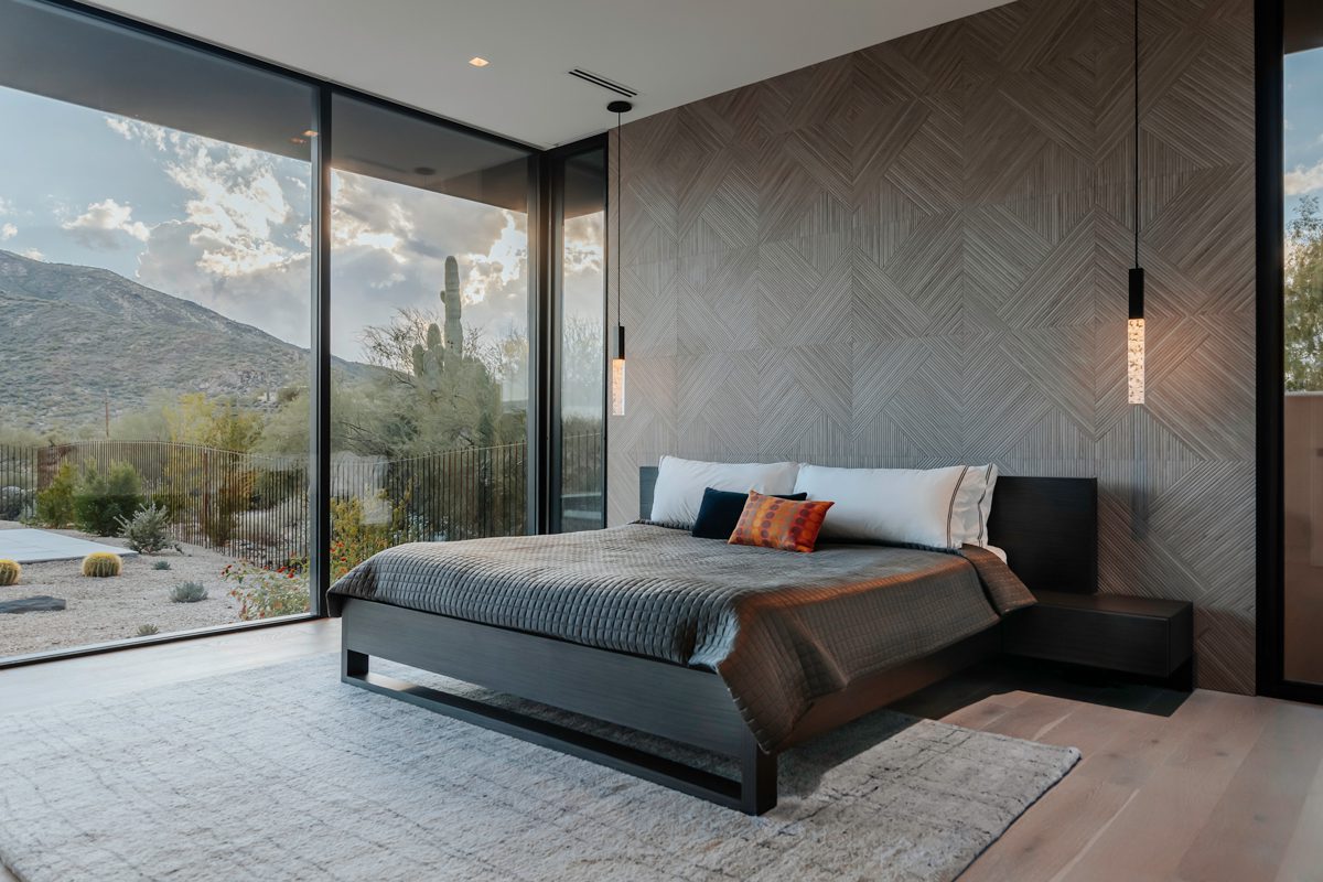 Modern master bedroom with expansive desert views through floor-to-ceiling glass walls