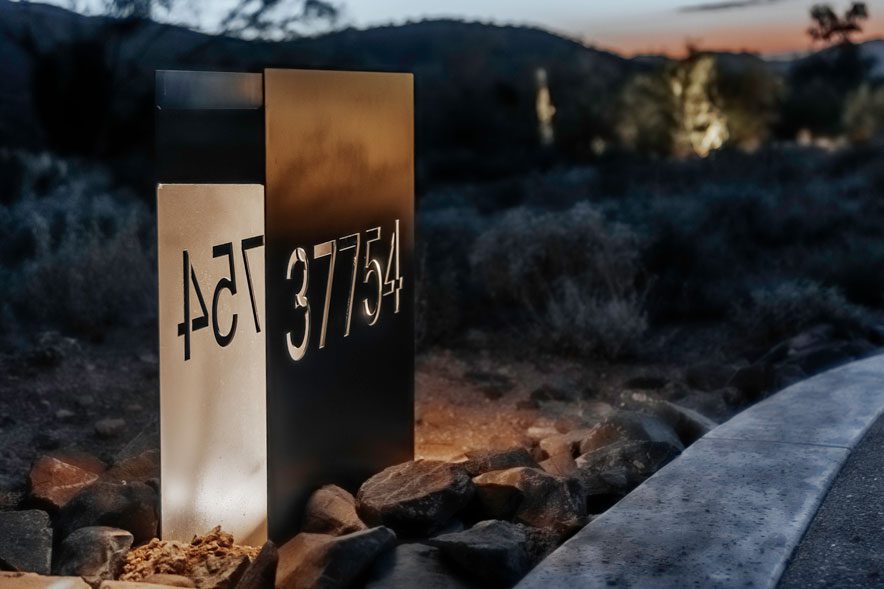 Modern metal address monument signage nestled among Carefree granite boulders